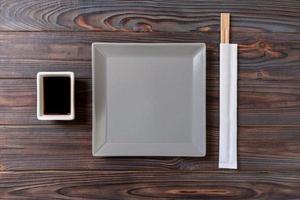 Empty gray square plate with chopsticks for sushi on wooden background. Top view with copy space photo