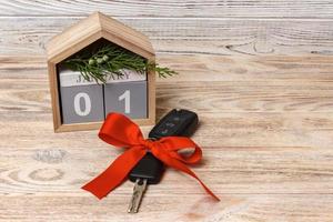 Close-up view of car keys with red bow as present and calendar on wooden background on wooden background photo