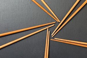 Many bamboo chopsticks on black slate background, textured, top view with opy space photo