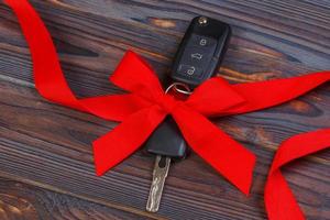 Close-up view of car keys with red bow as present on wooden background photo