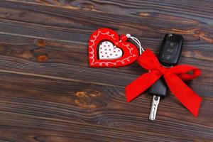 llave de coche con corazón rojo sobre fondo natural negro. regalo de navidad o día de san valentín o presente concepto abstracto foto