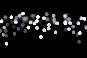 Bokeh white lights on black background, defocused and blurred many round light on background photo