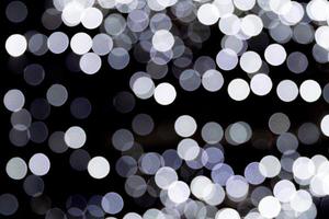 Bokeh white lights on black background. Abstract defocused many round light photo