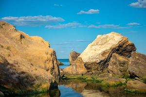 Seascape of calm blue ocean and rocky shore in the foreground photo