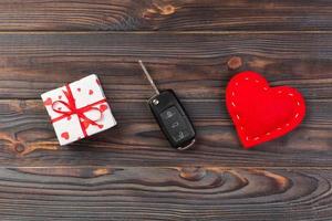 Valentine or other holiday handmade present in paper with red hearts, car keys and gifts box in holiday wrapper. box gift on Dark wooden table top view with copy space, empty space for design photo