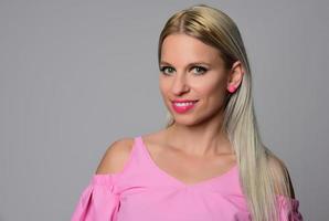 retrato de una hermosa joven con una linda camisa rosa y jeans azules posando en el estudio. concepto de belleza, emociones, expresión facial, estilo de vida, moda, cultura juvenil foto