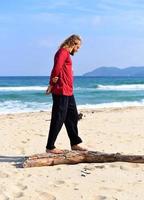 Man balancing on a log on the beach photo