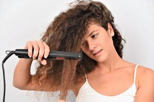 wavy-haired girl ironing straightening messy curls keratin therapy treatment photo