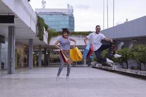 Portrait of cheerful Caucasian young couple man and woman holding many paper bags after shopping while walking and talking on street. Happy family couple with packages outdoor. Buying concept photo