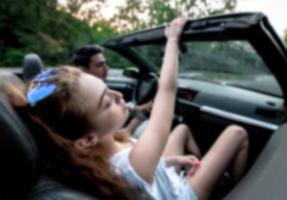 Friends having fun at car trip around the world. Couple in love with arms up on a convertible car. photo