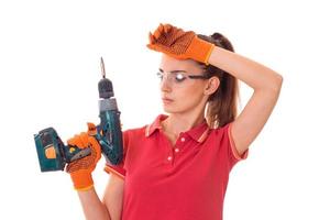 charming brunette lady makes refurbish an apartment with drill in hands isolated on white background in studio photo
