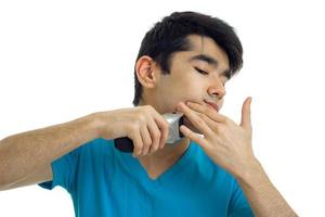 Cerca de un joven afeitándose la barba con una recortadora foto