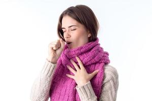 girl in a warm scarf coughs isolated on white background photo