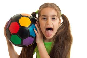 Portrait of a cheerful girl with a soccer ball shows tonque photo