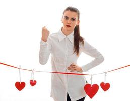 hermosa joven con camisa blanca y pintalabios rojo en los labios se encuentra cerca de la cinta con tarjetas en forma de corazón foto