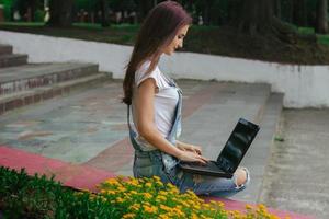 una joven esbelta sentada con una laptop foto