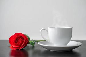 Red rose and coffee cup on the wood table photo