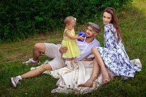 joven familia caucásica con su hija relajándose al aire libre a la hora del picnic foto