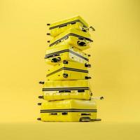 A stack of yellow travel suitcases on a yellow background. 3D rendering illustration. photo