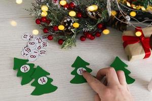 Advent calendar on wooden background with christmas tree branch and blur light. photo