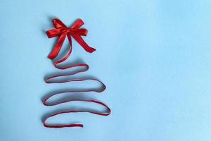 christmas tree made of satin red ribbon on blue background photo