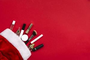 Flat lay composition with makeup products and Christmas decor on red paper background. Xmas, happy new year 2021, female wishes concept. photo