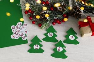Advent calendar on wooden background with christmas tree branch and blur light. photo