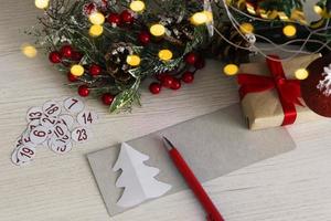 calendario de adviento sobre fondo de madera con rama de árbol de navidad y luz borrosa. foto