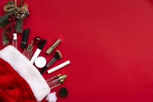 Flat lay composition with makeup products and Christmas decor on red paper background. Xmas, happy new year 2021, female wishes concept. photo