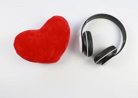 flat lay of heart shape pillow and headdphones on white background. photo