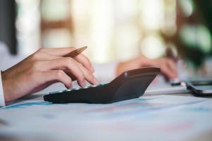 Business people use calculator to calculate documents, profit and loss statement review concept of company performance, effective tax deduction planning for individuals and companies paying tax rates photo