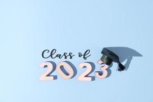Class of 2023 concept. Numbers 2023 with black graduated cap on colored background photo