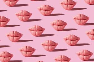 Pattern from pink lips on pink background. Creative beauty concept background photo