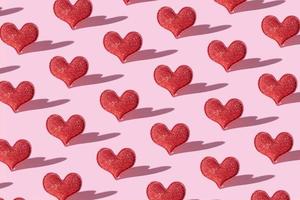 Pattern with red glitter heart shape on pink background with hard shadow.  Valentines day minimalistic symbol love photo