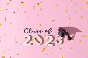 Class of 2023 concept. Numbers 2023 with black graduated cap on colored background photo