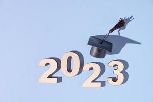 Class of 2023 concept. Numbers 2023 with black graduated cap on colored background photo