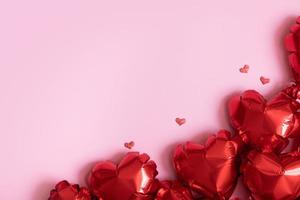 Red heart shape foil baloons on pink background. Valentines Day background with copy space photo