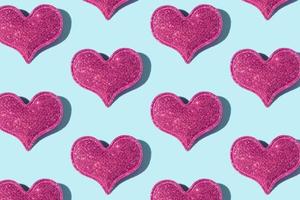 Pattern made from glitter heart shape on colored background with hard shadow. Valentines day minimalistic design photo