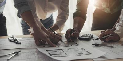 reunión de trabajo en equipo de ingenieros, trabajo de dibujo en la reunión de planos para el trabajo del proyecto con un socio en la construcción de modelos y herramientas de ingeniería en el concepto de sitio de trabajo, construcción y estructura. foto