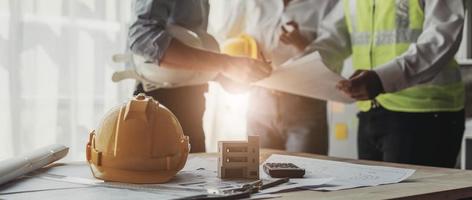 Los equipos de ingenieros civiles que se reúnen trabajando juntos usan cascos de trabajador en el sitio de construcción en la ciudad moderna. trabajo en equipo del ingeniero del jefe de proyecto de la industria del capataz. equipo profesional de la industria asiática foto