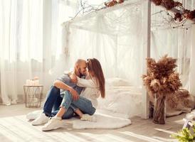 Beautiful couple in love hugs and kisses in white room photo