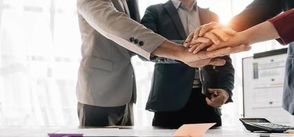 Group of business people putting their hands working together on wooden background in office. group support teamwork agreement concept. photo