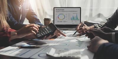 Business People Meeting using laptop computer,calculator,notebook,stock market chart paper for analysis Plans to improve quality next month. Conference Discussion Corporate Concept photo