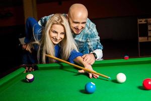 Beautiful cheerful couple plays billiard photo