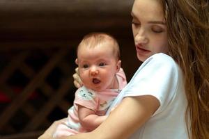 encantadora madre joven con una niña pequeña en las manos foto