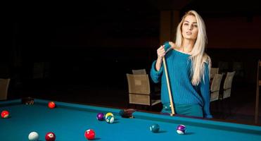 Fashion portrait of beautiful young blonde girl plays billiard photo