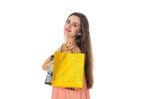una chica con el pelo largo se estira hacia adelante un paquete amarillo de una tienda aislada de fondo blanco foto