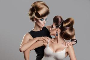 Studio photo of two beauty women with creative hairstyle looking at each others