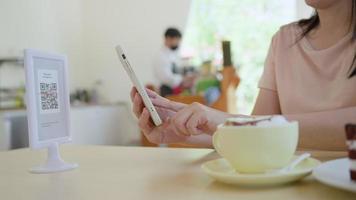 Woman use smartphone to scan QR code to pay in cafe restaurant with a digital payment without cash. Choose menu and order accumulate discount. E wallet, technology, pay online, bank app, scanning video