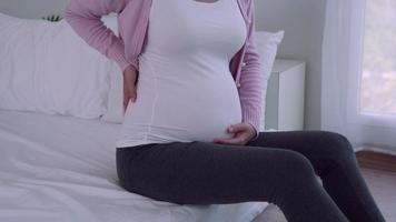 les femmes enceintes tapotent doucement l'estomac avec les mains. les femmes enceintes se sentent mal à l'aise et ont mal au dos en raison de la prise de poids due à l'augmentation de l'âge gestationnel. symptômes conceptuels de la grossesse. video